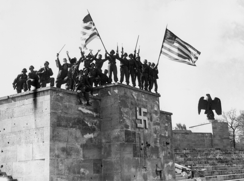 Men of the 45th division of the U.S. 7th Army wave American flags from the dais of the Luitpold Arena in Nuremberg, where annual Nazi party rallies were held.